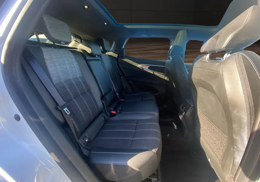 Vue intérieure côté gauche des sièges arrière noirs du Renault Austral 2025 avec toit panoramique et lumière naturelle.