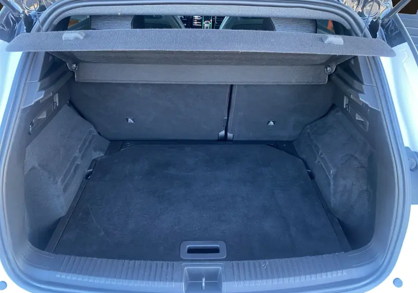 Coffre ouvert vu de l'arrière d'un Renault Austral blanc nacré avec intérieur noir et cache-bagages déployé.