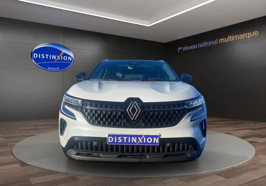 Vue frontale d'un Renault Austral blanc nacré avec toit noir, calandre noire et logo Renault central bien visible.