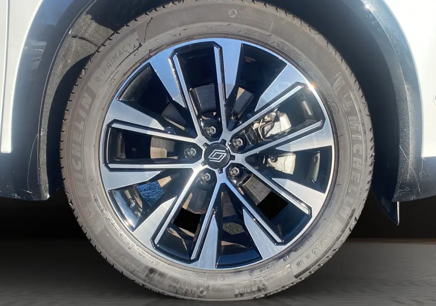 Gros plan sur la jante alu 19'' noire et argentée du Renault Austral blanc nacré, roue avant côté gauche.