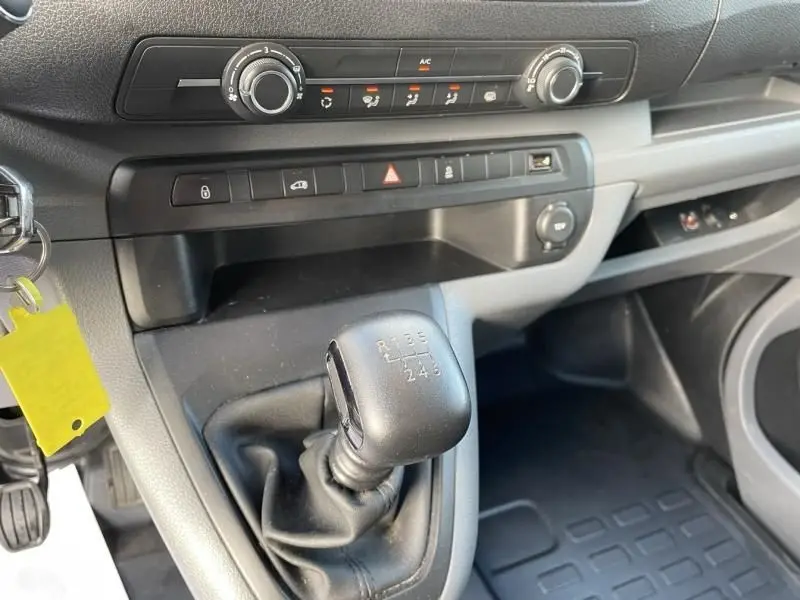 Gros plan sur la console centrale intérieure du Peugeot Expert Fourgon gris métal, mettant en valeur le levier de vitesse manuel et les commandes de climatisation.