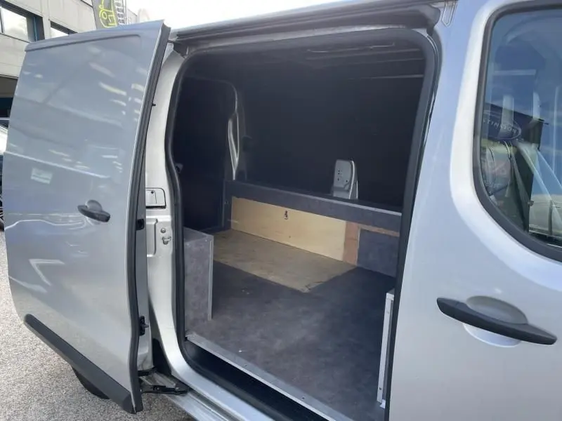 Vue latérale gauche du Peugeot Expert Fourgon gris métal 2018 avec porte coulissante ouverte dévoilant l'espace de chargement vide.