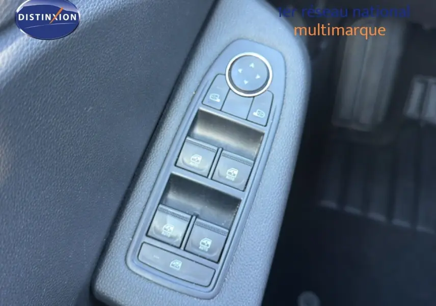 Gros plan sur la commande des vitres électriques côté conducteur d’une Renault Clio blanche, intérieur noir.