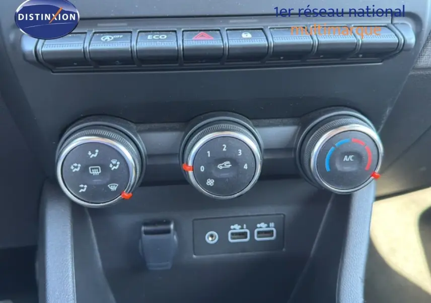 Gros plan sur les commandes de climatisation et les ports USB du tableau de bord d’une Renault Clio blanche 2025.