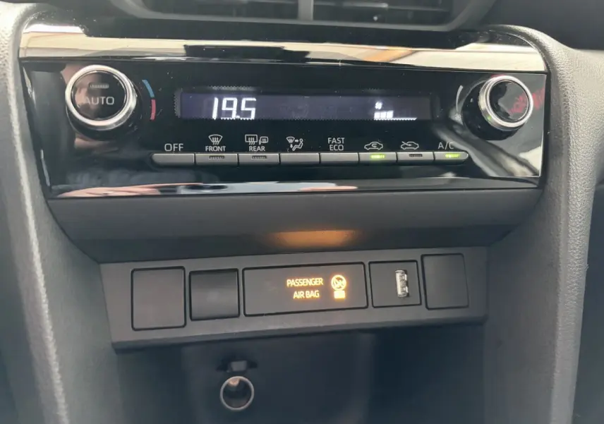 Gros plan sur la console centrale de la Toyota Yaris Cross 2024 gris clair, affichant la climatisation digitale à 19,5°C.