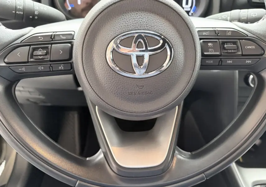 Vue rapprochée du volant cuir multifonctions gris foncé de la Toyota Yaris Cross 2024, avec commandes intégrées.