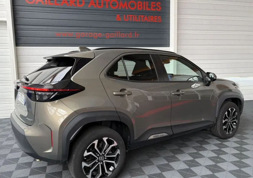 Vue 3/4 arrière droite d'une Toyota Yaris Cross gris clair 2024 avec jantes alliage et feux arrière LED.