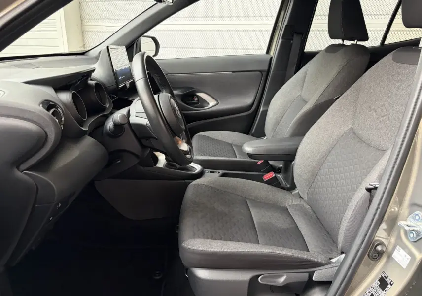 Vue intérieure côté conducteur de la Toyota Yaris Cross 2024 gris clair, volant cuir multifonctions et sièges tissu gris.