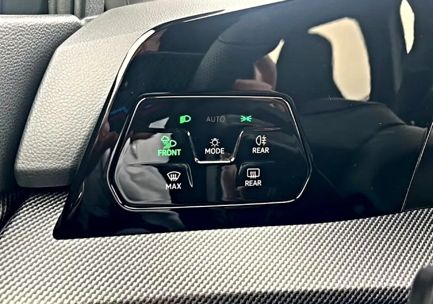 Gros plan sur les commandes d’éclairage et de désembuage avec finition noire brillante et insert carbone dans une Volkswagen Golf noire 2026.