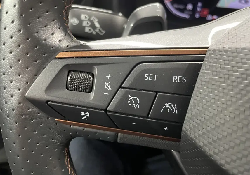 Gros plan sur les commandes du volant du CUPRA Formentor 1.5 TSI 150 DSG7, cuir perforé et finition brun cuivré.