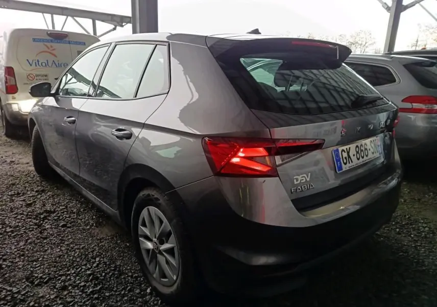 Vue 3/4 arrière gauche d'une Skoda Fabia gris graphite 2022 avec feux arrière allumés et jantes 15 pouces.