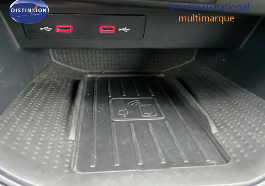 Vue rapprochée de la console centrale du SEAT Arona 2025, avec chargeur sans fil et ports USB rouges visibles.