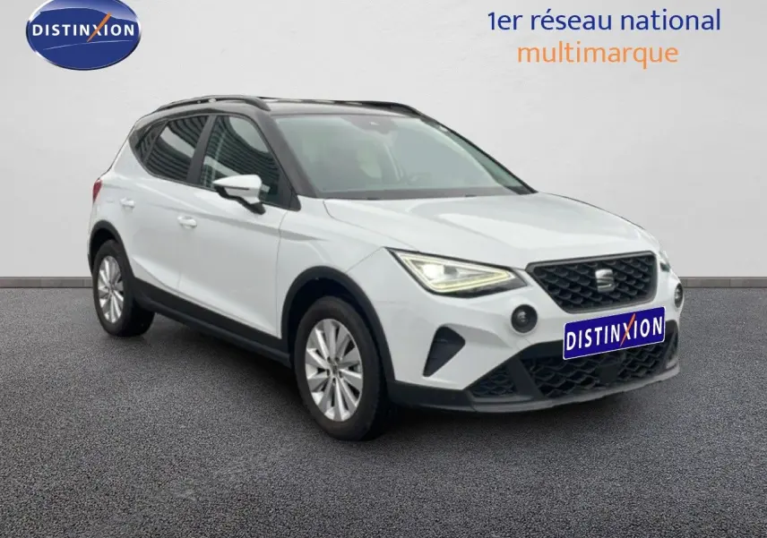 SEAT Arona blanc alpin métal avec toit noir, vue 3/4 avant droit, phares allumés sur fond neutre.