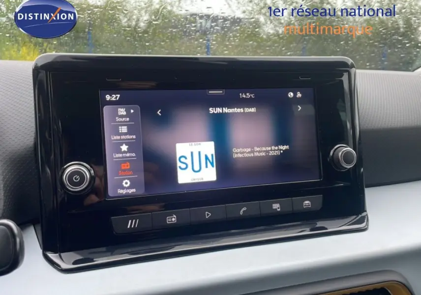 Écran tactile central du tableau de bord d'une SEAT Arona 2025, affichant une radio numérique sous pluie.