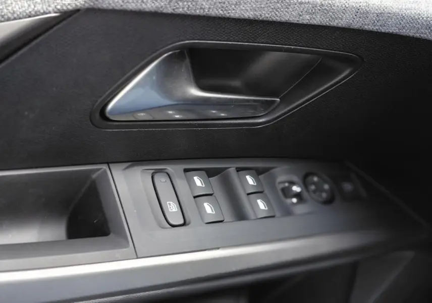 Gros plan sur la commande des vitres et la poignée intérieure côté gauche d’une Peugeot 3008 Hybrid noire, finition Allure.