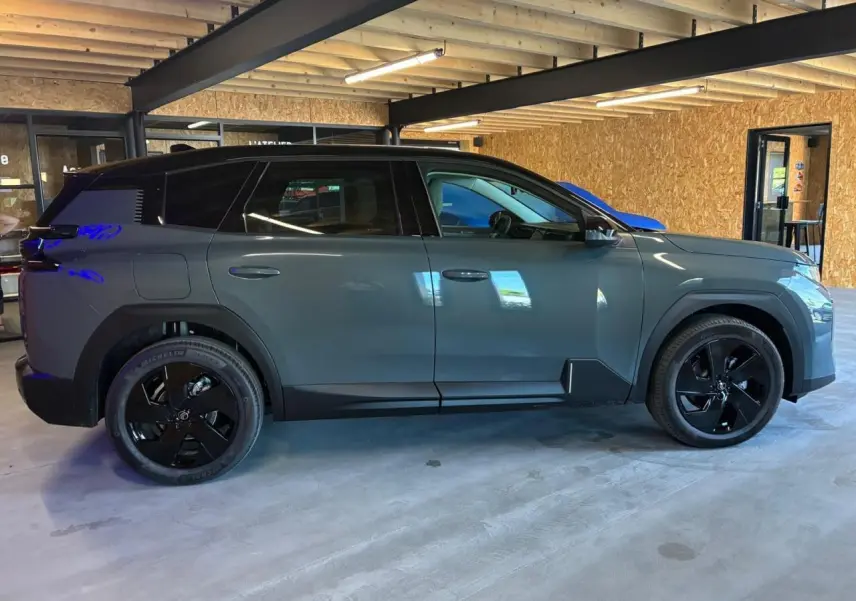 Profil droit du Citroën C5 Aircross II vert avec toit noir et jantes noires dans un garage intérieur.