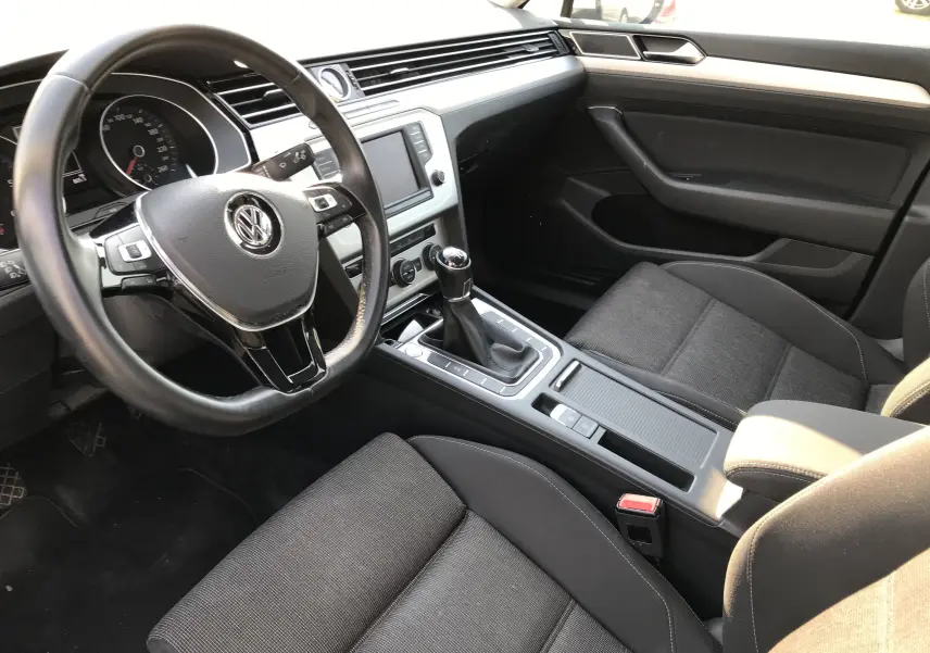 Intérieur de la Volkswagen Passat Confortline Business 2015, vue côté conducteur, volant cuir et console centrale avec boîte manuelle.
