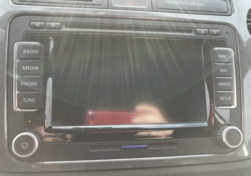 Écran tactile central du tableau de bord du Volkswagen Tiguan blanc 2013 avec commandes radio et navigation visibles.