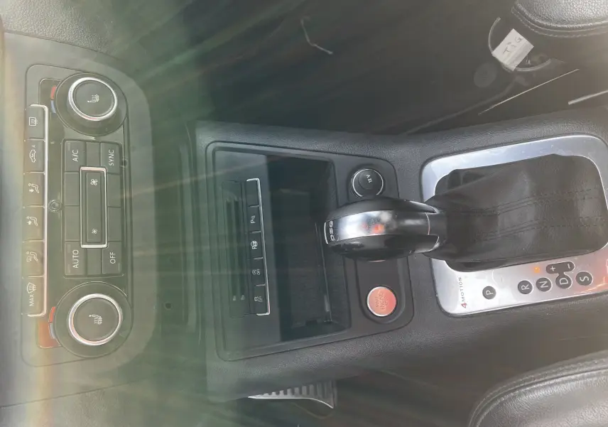 Vue rapprochée de la console centrale noire du Volkswagen Tiguan blanc 2013, avec levier de vitesse DSG et commandes climatisation.