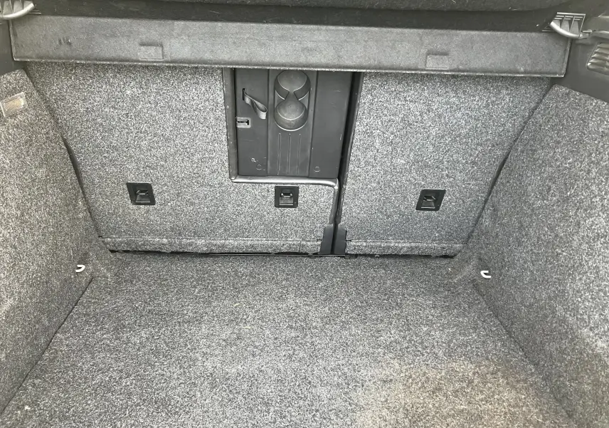 Vue intérieure du coffre gris d'un Volkswagen Tiguan 2013, montrant le revêtement et une trappe centrale.