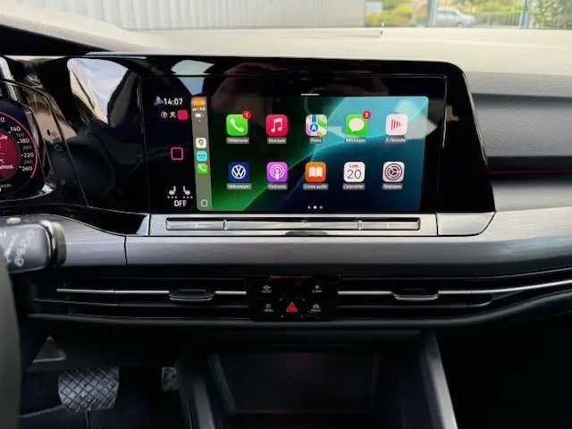 Tableau de bord de Volkswagen Golf VIII gris dauphin, écran tactile central affichant des applications connectées en plein jour.