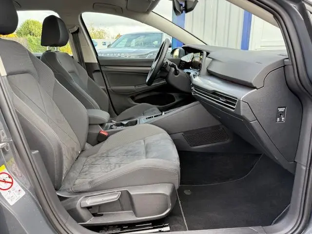 Intérieur côté passager de la Volkswagen Golf VIII gris dauphin, sièges tissu gris et tableau de bord moderne avec écran tactile.