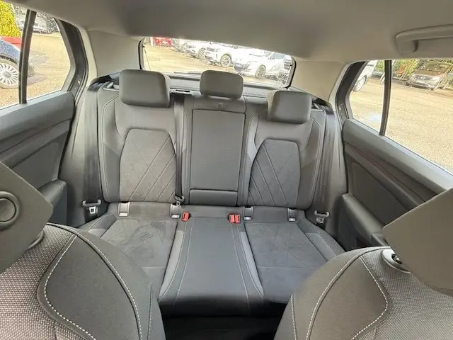 Vue intérieure arrière de la Volkswagen Golf VIII gris dauphin, montrant les sièges arrière en tissu avec appuie-têtes.