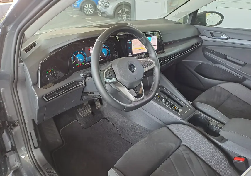 Intérieur côté conducteur de la Volkswagen Golf VIII gris dauphin, tableau de bord digital et volant multifonction moderne.