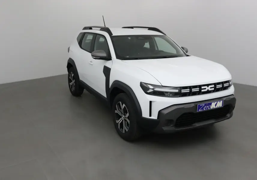 Dacia Duster 2025 blanc glacier en 3/4 avant droit, avec calandre noire et jantes alliage 17 pouces.