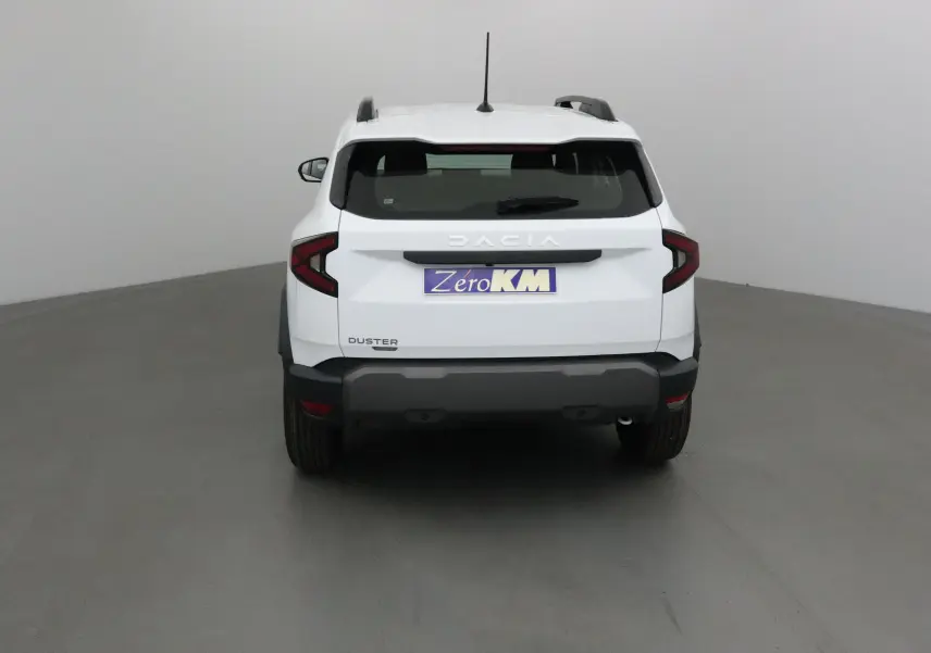 Vue arrière du Dacia Duster blanc glacier 2025, mettant en valeur ses feux arrière en forme de C et son pare-chocs noir robuste.