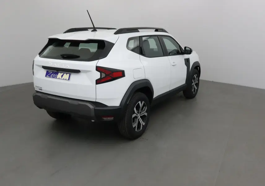 Vue 3/4 arrière droit du Dacia Duster blanc glacier 2025 avec protections noires et jantes alliage.