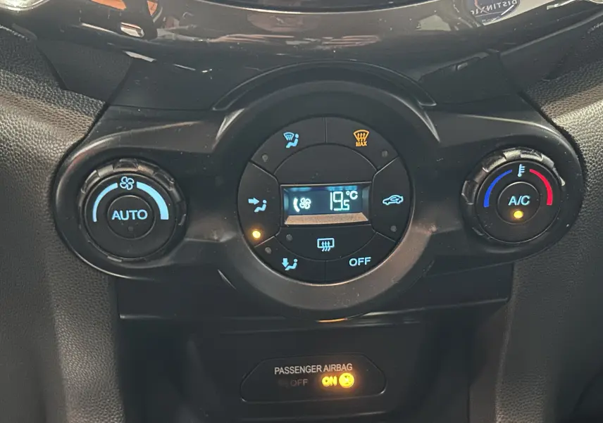 Gros plan sur la commande de climatisation automatique du Ford EcoSport gris, affichant 19,5°C et témoin airbag passager allumé.