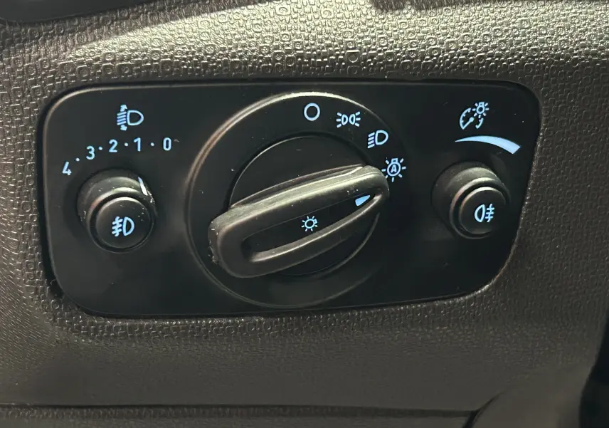 Gros plan sur le panneau de commande des phares du Ford EcoSport gris, avec réglages des feux et antibrouillards visibles.