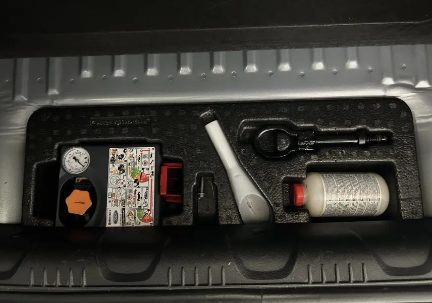 Gros plan sur le kit de réparation pneumatique dans le coffre d'un Ford EcoSport gris 2018, version Titanium.