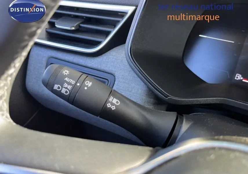 Gros plan sur la commande des phares et clignotants à gauche du volant dans l’habitacle d’une Renault Clio gris schiste métal.