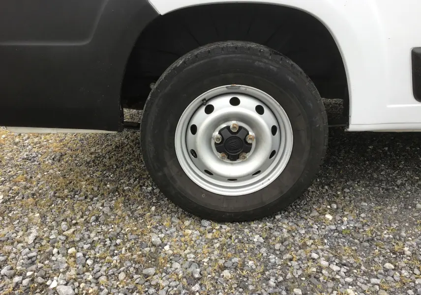 Gros plan sur la roue avant gauche du FIAT Ducato blanc, avec jante acier et partie basse de la carrosserie visible.