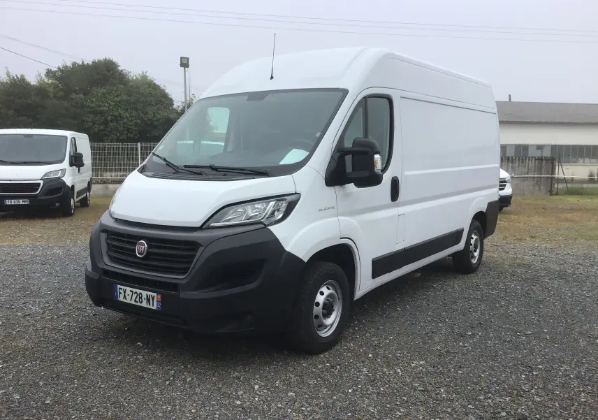 Vue 3/4 avant droite du fourgon blanc Fiat Ducato 35 MH2 avec pare-chocs noir et rétroviseurs électriques.