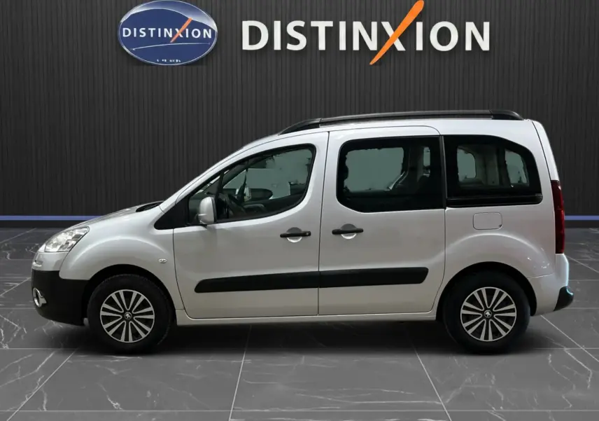 Profil droit d'un Peugeot Partner Tepee gris aluminium de 2013, avec barres de toit et vitres arrière teintées.