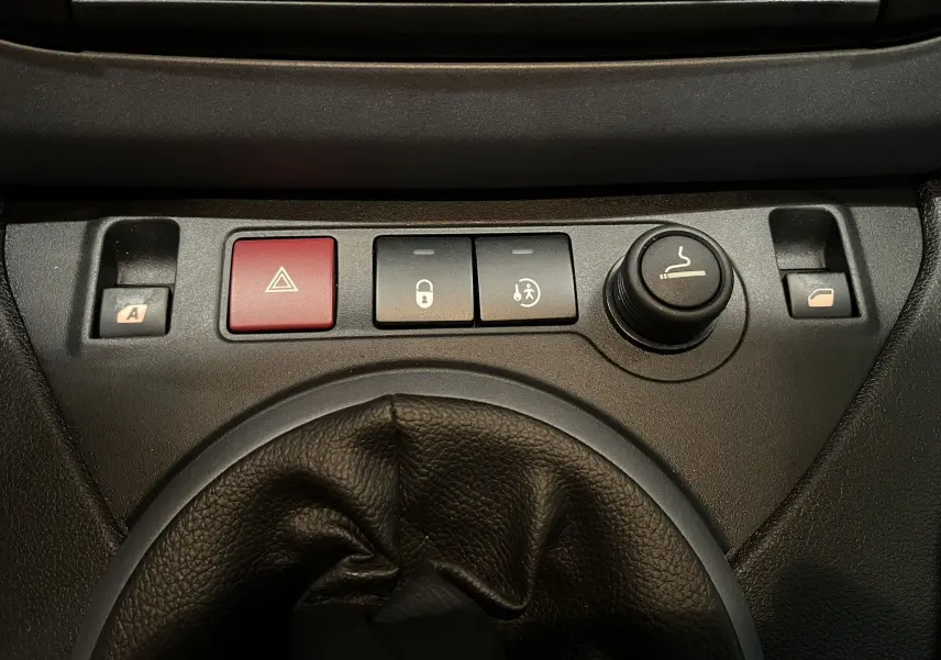 Gros plan sur la console centrale du Peugeot Partner Tepee 2013, montrant les boutons de verrouillage, warning et allume-cigare.