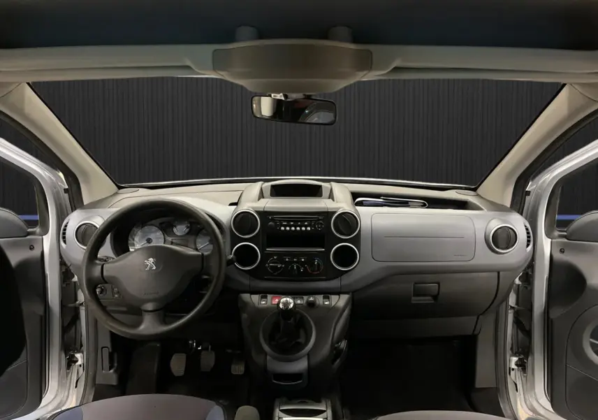 Vue frontale de l’intérieur gris du Peugeot Partner Tepee 2013 avec volant, tableau de bord et portes ouvertes.