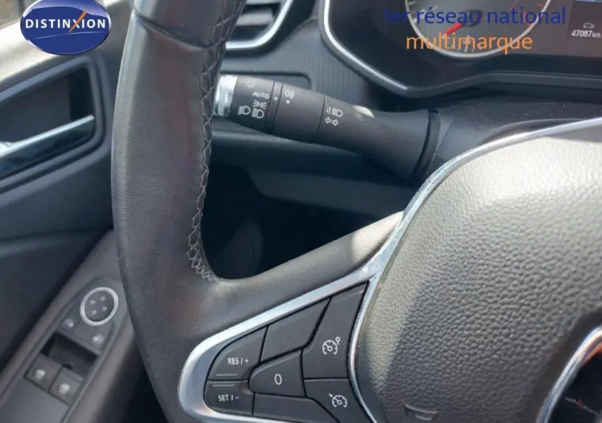 Vue rapprochée du volant de la Renault Clio blanc 2020, avec commandes de régulateur de vitesse et tableau de bord partiel.