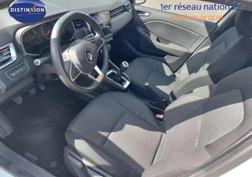 Vue intérieure côté conducteur de la Renault Clio blanche 2020, avec volant multifonction et boîte manuelle visible.