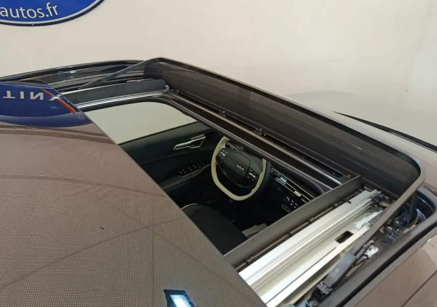 Vue plongeante sur le toit ouvrant panoramique gris clair du Kia Sportage 2026, avec aperçu intérieur et volant.