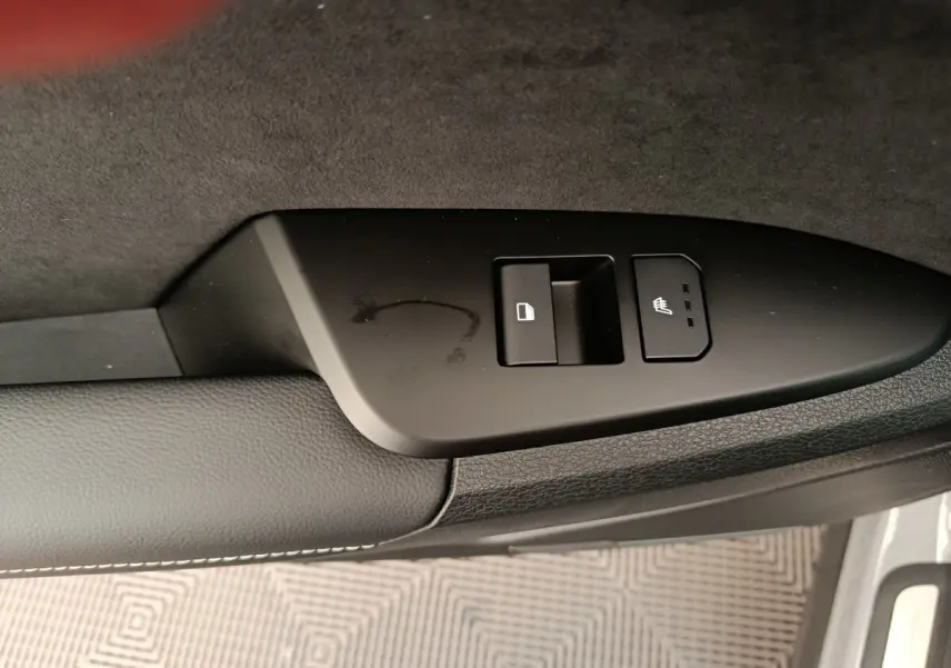 Détail de la commande de verrouillage et de siège chauffant sur la portière côté conducteur du KIA Sportage gris clair.