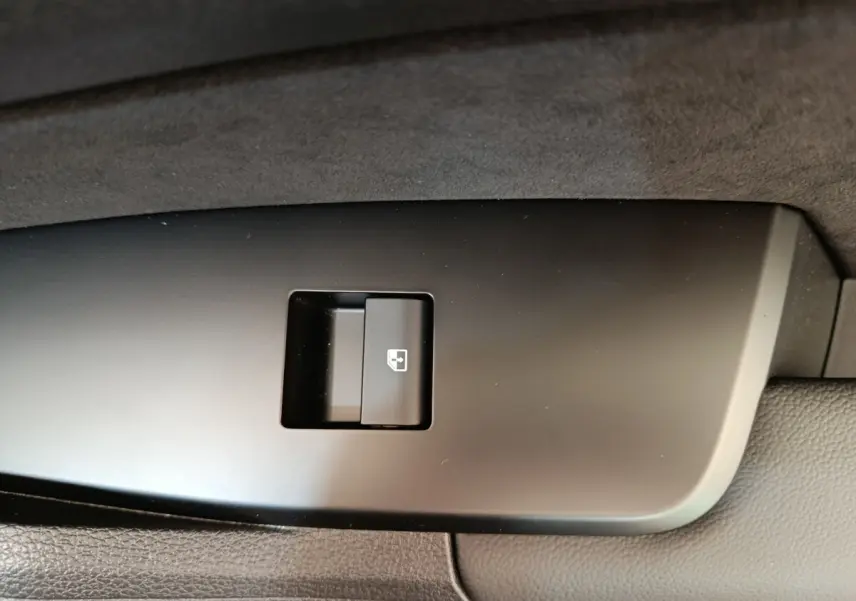 Bouton de commande de lève-vitre sur panneau de porte intérieur noir du KIA SPORTAGE gris clair.