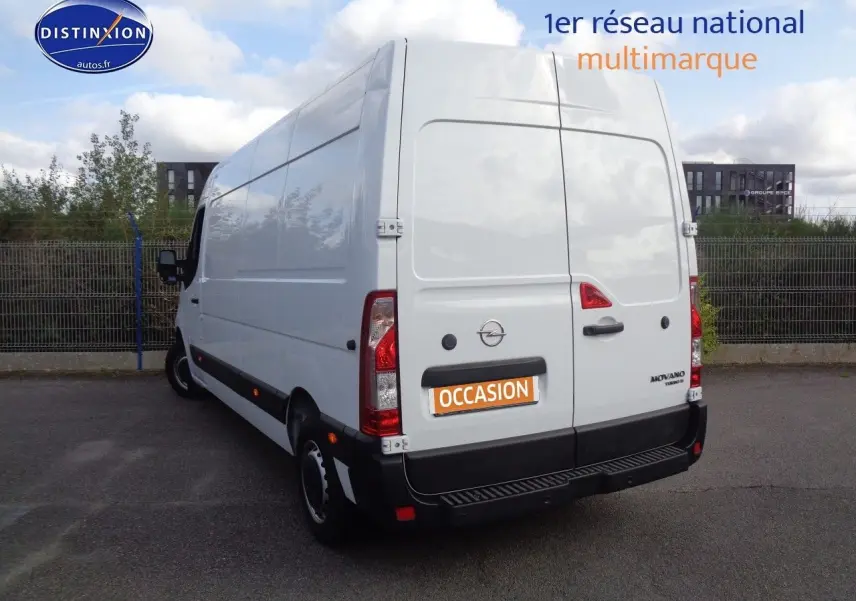 Vue 3/4 arrière gauche d'un Opel Movano Fourgon blanc polaire avec portes arrière fermées sur un parking extérieur.