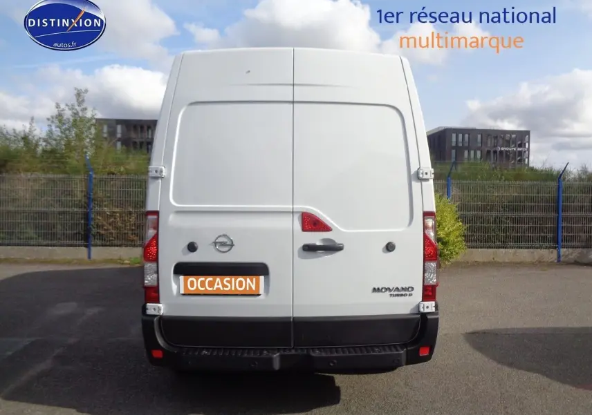 Vue arrière d’un fourgon Opel Movano blanc polaire avec portes battantes et logo distinctif sur parking.
