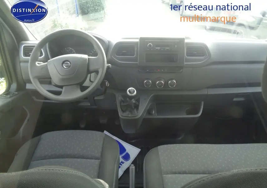 Intérieur de l'Opel Movano Fourgon 2022, vue frontale du tableau de bord avec volant, levier de vitesse manuel et sièges gris.