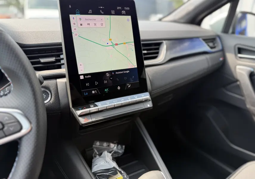 Vue intérieure du tableau de bord du Renault Captur 2025, écran tactile vertical affichant la navigation, finition moderne noire.