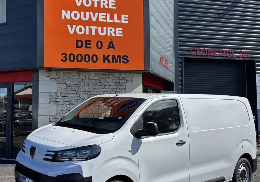 Peugeot Expert Fourgon blanc en 3/4 avant droit, stationné devant un bâtiment commercial avec panneau orange.